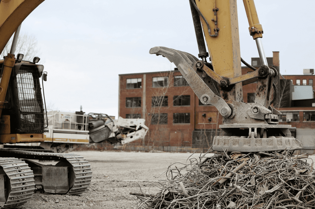 A crane trying to pick up iron scrap using a large magnet